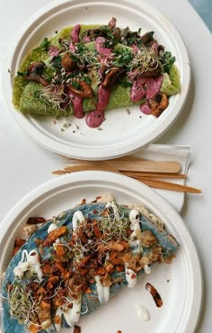 two white plates topped with food on top of a table