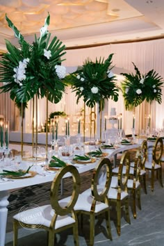 the tables are set with white and gold chairs, green centerpieces, and greenery