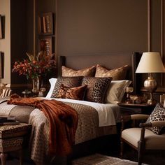 a large bed sitting in a bedroom next to a chair and table with flowers on it