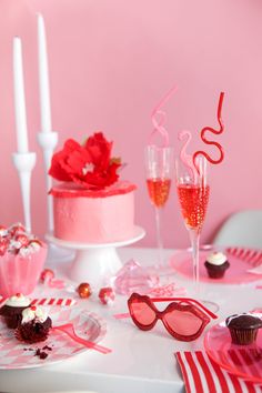 a table topped with cupcakes and pink glasses