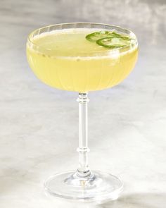 a glass filled with yellow liquid and garnished with cucumber