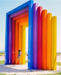 a woman is standing in front of an art installation made of multicolored columns