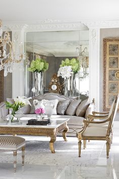 a living room filled with lots of furniture and flowers on top of a coffee table