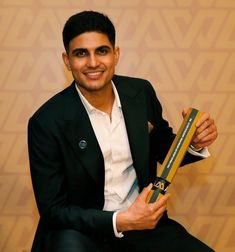 a man sitting on a chair holding an award