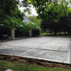 an empty parking lot surrounded by trees in the middle of a yard with no cars on it