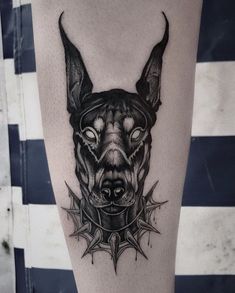 a black and grey dog's head with spikes on his leg, tattoo style