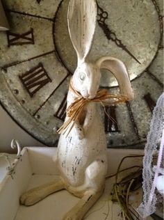 a white rabbit figurine sitting on top of a table next to a clock