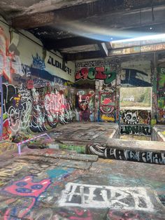 an abandoned skateboard park with graffiti all over the walls and floor, along with other graffiti on the walls