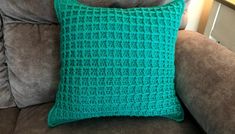 a green crocheted pillow sitting on top of a couch