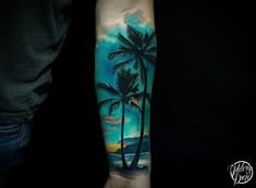 a man's arm with a palm tree and ocean scene tattoo on the left forearm