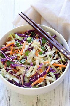 a white bowl filled with coleslaw and carrots next to chopsticks