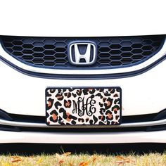 an animal print license plate on the front of a white car with a monogrammed design