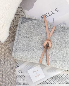 a pile of blankets sitting on top of a white rug next to a pillow and book