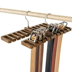 two pairs of shoes hang from a wooden rack with metal clips on it's sides