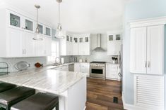 a large kitchen with white cabinets and marble counter tops, along with stainless steel appliances