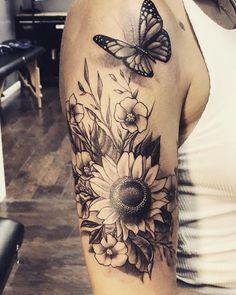 a woman's arm with flowers and a butterfly on the back of her shoulder