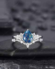 a blue and white fire opal ring on top of a rock