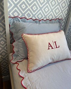 a bed with blue and white bedspread, red trimmings and pillows