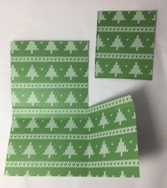 two pieces of green and white knitted fabric with christmas trees on the front, one is