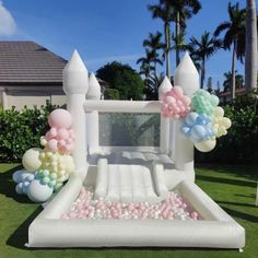 an inflatable bouncer with balloons and flowers on the lawn at a party