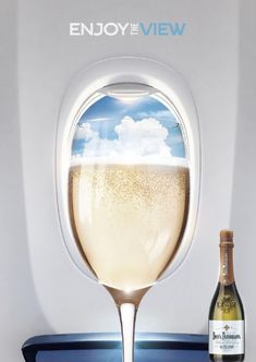 a bottle of wine sitting on top of an airplane window sill next to a glass filled with liquid