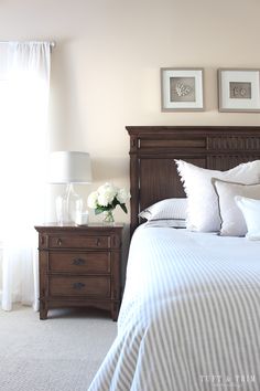 a bedroom with a bed, nightstands and two pictures on the wall above it