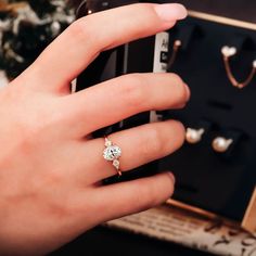 a woman's hand holding a cell phone with an engagement ring on it