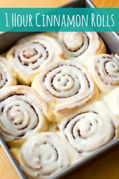 a pan filled with cinnamon rolls on top of a wooden table