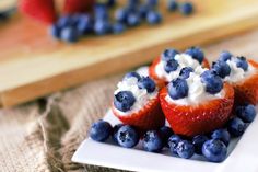 some strawberries and blueberries are on a plate with whipped cream toppings in them