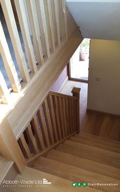 an overhead view of a wooden staircase with wood handrails and hardwood flooring