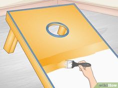 a person using a brush to paint a large yellow object with white paint on it