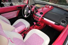 the interior of a red car with pink and white leather seats, steering wheel cover and dashboard