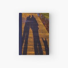 the shadow of two people standing on a wooden walkway