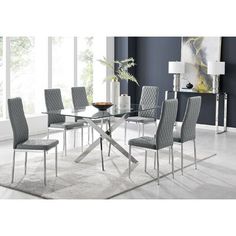 a glass dining table with grey chairs and white rug in front of blue painted walls