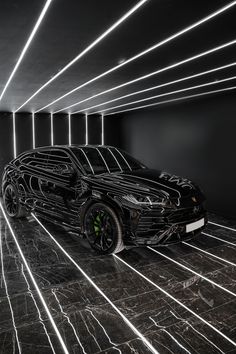 a black sports car parked in a dark room with neon lights on the walls and floor