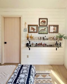 a bed sitting in a bedroom next to a wall with pictures on it and shelves