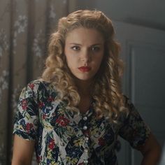 a woman with long blonde hair wearing a floral shirt