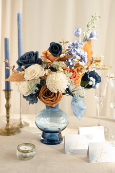 a vase filled with lots of flowers sitting on top of a table next to candles