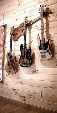 three guitars are hanging on the wall