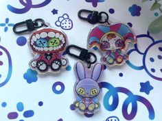 three keychains with cartoon characters on them sitting on a table next to flowers