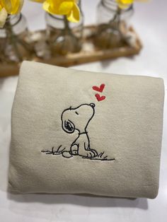 a small pillow with a drawing of a snoopy dog holding a red heart on it