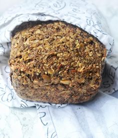 a piece of bread with nuts on it sitting on top of a cloth covered tablecloth