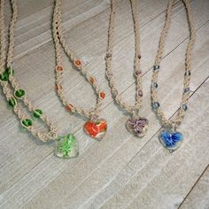 four necklaces with different colored glass hearts on them