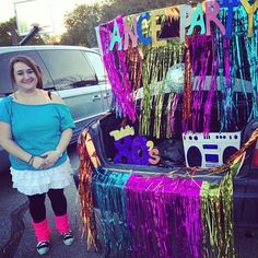 a woman standing in front of a trunk filled with toys and confetti decorations