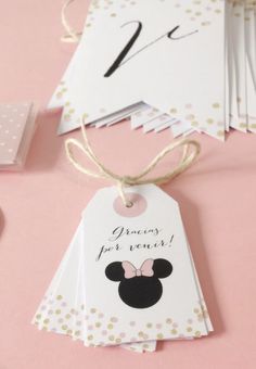 some tags that are on top of a pink table with confetti and scissors