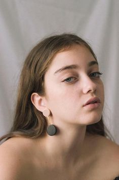 a young woman wearing large earrings looking off to the side