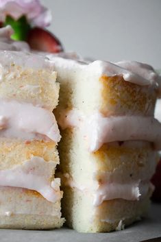 two pieces of cake with frosting and strawberries in the background