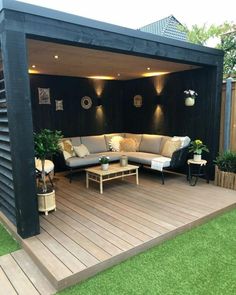 an outdoor living area with couches, tables and plants on the decked patio