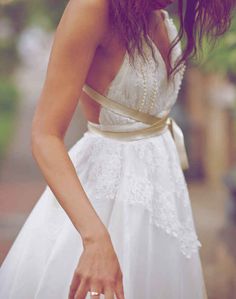 a woman in a white dress is holding her hand out to the side and looking down