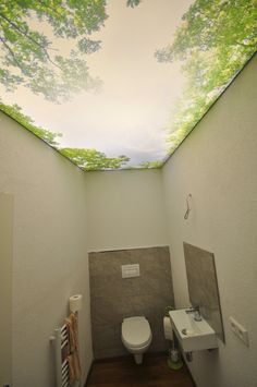 a bathroom with a toilet, sink and trees painted on the ceiling in it's walls